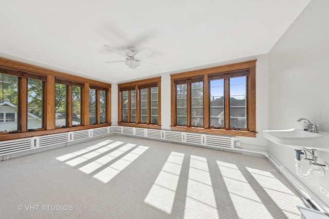 unfurnished sunroom with ceiling fan, plenty of natural light, and carpet