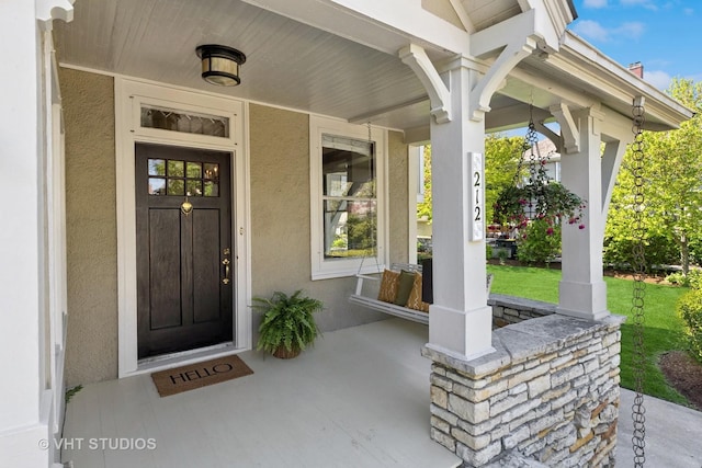 doorway to property with a porch and stucco siding