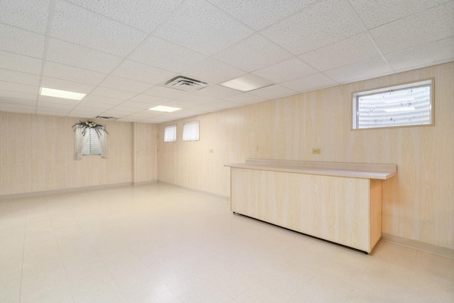 9228 Ridgeland Ave, Oak Lawn, IL 60453 - basement with a paneled ceiling, light floors, and wooden walls