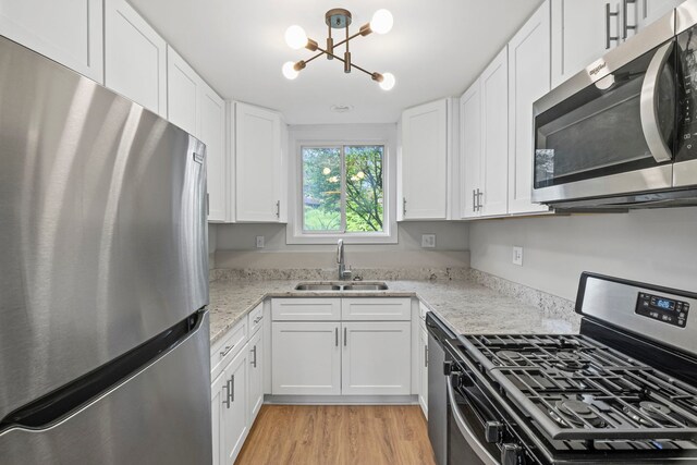 764 Terrace Ct Unit A, Elgin, IL 60120 - kitchen featuring light wood-style flooring, a sink, a notable chandelier, white cabinets, and appliances with stainless steel finishes