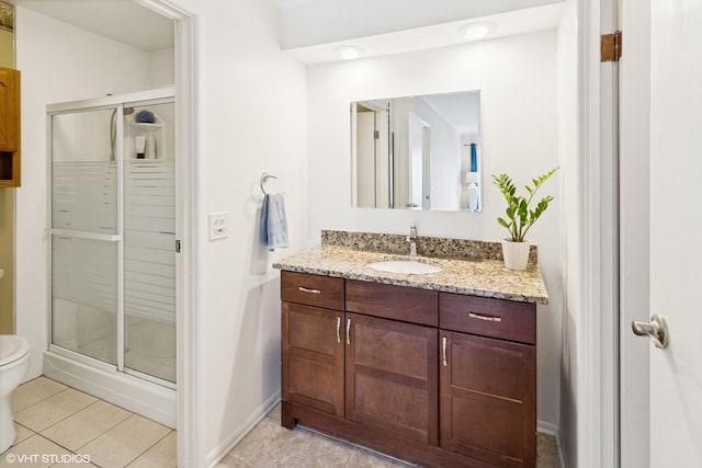 bathroom featuring toilet, vanity, tile patterned floors, a shower stall, and baseboards