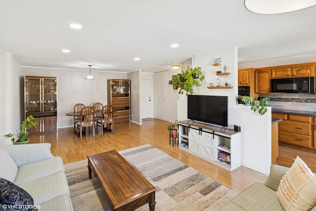 living area with baseboards, light wood-type flooring, and recessed lighting