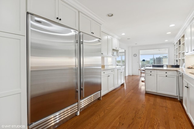 kitchen with stainless steel built in fridge, white cabinets, dark wood finished floors, a peninsula, and recessed lighting