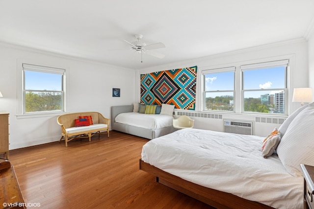 bedroom featuring ornamental molding, wood finished floors, baseboards, radiator heating unit, and a ceiling fan
