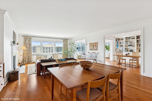 dining space featuring ornamental molding, wood finished floors, a fireplace, and baseboards