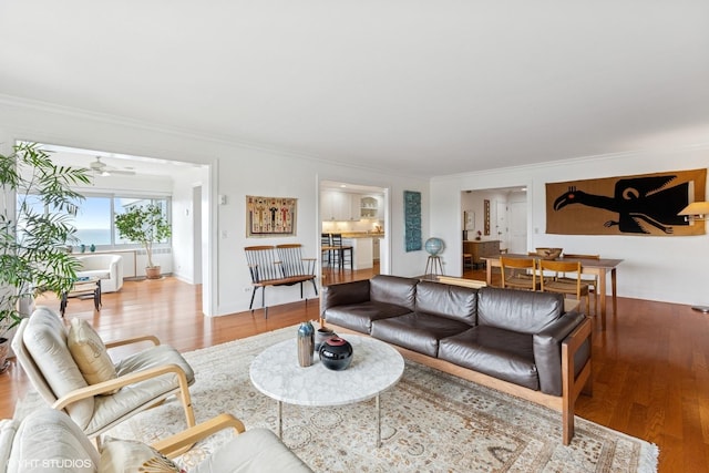 living area featuring crown molding, wood finished floors, and a ceiling fan