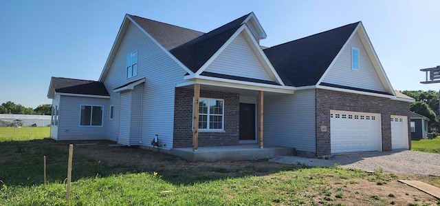 24415 W Quail Dr, Channahon, IL 60410 - traditional home with covered porch, brick siding, dirt driveway, a front lawn, and a garage