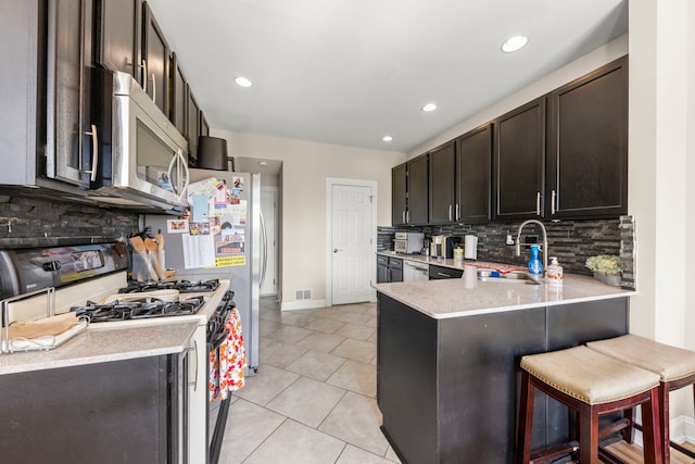 8529 Sawyer Ct, Joliet, IL 60431 - kitchen featuring appliances with stainless steel finishes, a sink, decorative backsplash, a peninsula, and recessed lighting