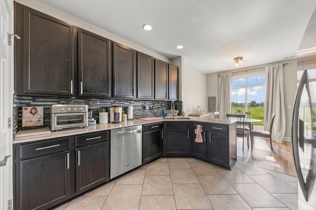 8529 Sawyer Ct, Joliet, IL 60431 - kitchen with stainless steel dishwasher, a sink, a peninsula, decorative backsplash, and light tile patterned floors