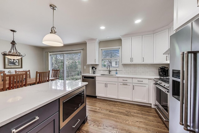 962 Thompson Blvd, Buffalo Grove, IL 60089 - kitchen with high quality appliances, a sink, decorative light fixtures, white cabinetry, and decorative backsplash