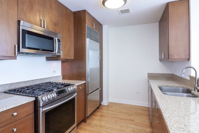 60 E Monroe St Unit 2705, Chicago, IL 60603 - kitchen with stainless steel appliances, a sink, light wood-type flooring, baseboards, and brown cabinetry