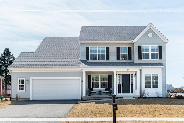 traditional-style house featuring roof with shingles, a porch, aphalt driveway, and an attached garage