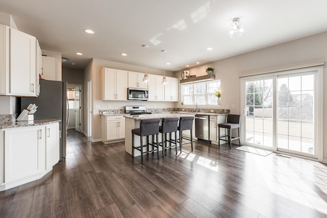 kitchen featuring white cabinetry, stainless steel appliances, a center island, and a kitchen bar