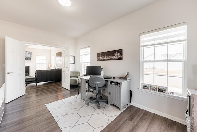 home office with plenty of natural light, wood finished floors, and baseboards