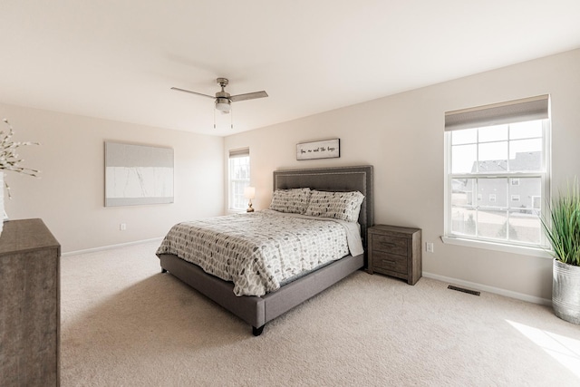 bedroom featuring visible vents, baseboards, ceiling fan, and light carpet