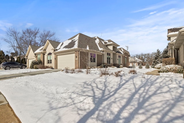 view of snowy exterior featuring brick siding, a residential view, and a garage