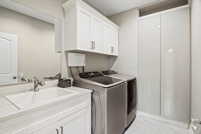 washroom with cabinet space, independent washer and dryer, marble finish floor, and a sink