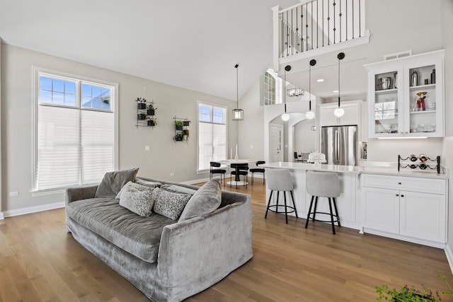 living room with arched walkways, light wood finished floors, and a high ceiling