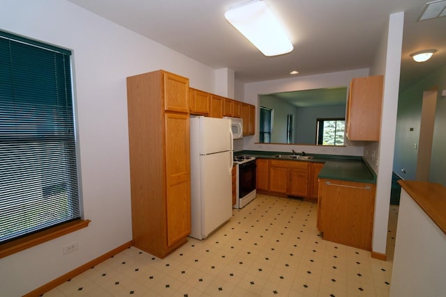 3404 Steeplechase Way, Grayslake, IL 60030 - kitchen with white appliances, dark countertops, a sink, baseboards, and light flooring
