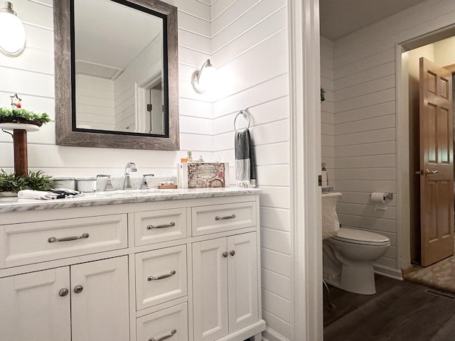 full bathroom with a shower stall, wooden walls, toilet, and wood finished floors
