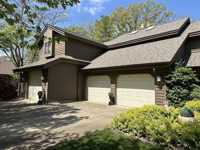 exterior space featuring an attached garage, a shingled roof, and driveway