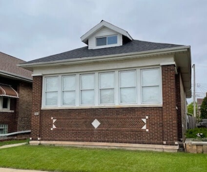 view of side of home featuring brick siding and a yard