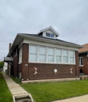 view of side of property featuring brick siding and a yard