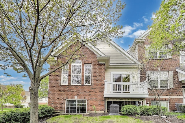 rear view of property with central air condition unit, brick siding, and a balcony