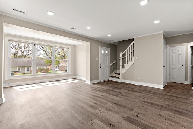 unfurnished living room with wood finished floors, visible vents, baseboards, and stairway