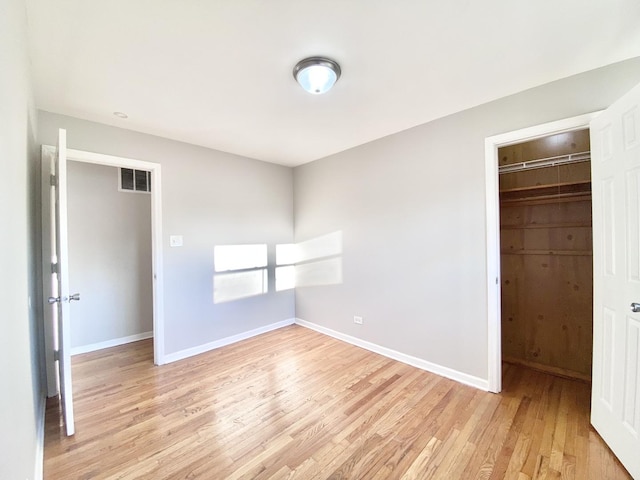 unfurnished bedroom with baseboards, a closet, light wood-style flooring, and visible vents