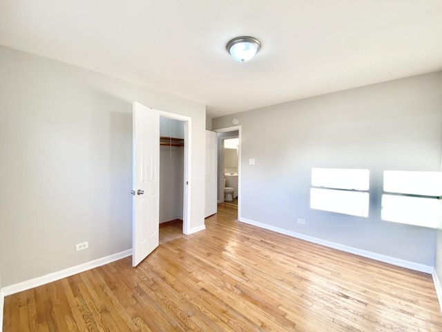 unfurnished bedroom with a closet, baseboards, and light wood-style flooring