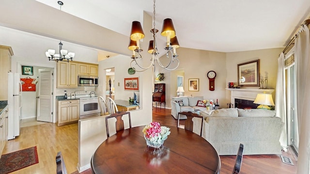 420 58th Pl, Hinsdale, IL 60521 - dining room featuring a chandelier, light wood-type flooring, vaulted ceiling, and a tile fireplace