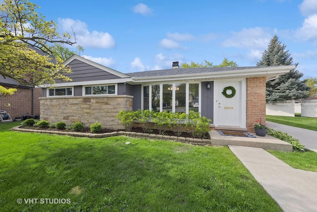 ranch-style home featuring a front lawn, stone siding, and a chimney