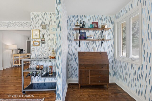 detailed view of wallpapered walls, baseboards, and wood finished floors