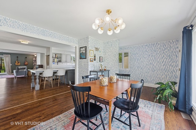 dining space featuring wallpapered walls, wood finished floors, and a chandelier