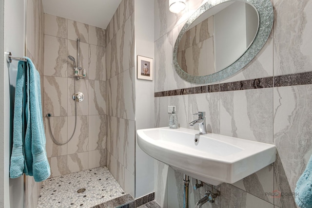 full bath featuring a tile shower, a sink, and tile walls