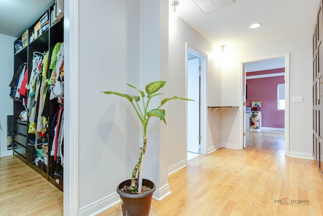hallway with light wood finished floors, baseboards, and recessed lighting