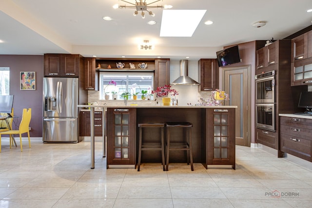 kitchen featuring stainless steel appliances, wall chimney range hood, light countertops, tasteful backsplash, and recessed lighting