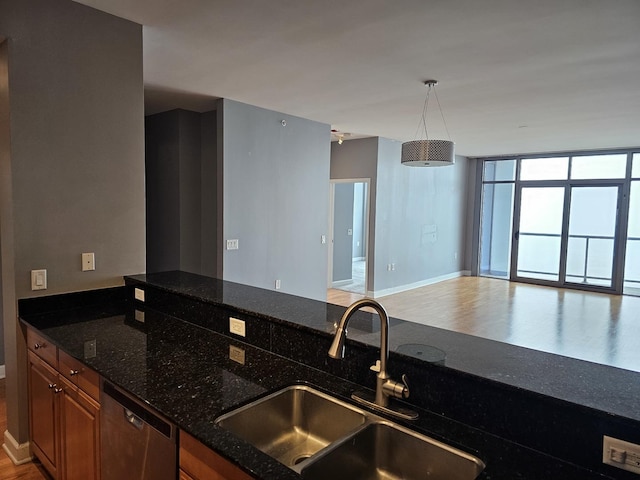 kitchen with brown cabinets, a sink, open floor plan, baseboards, and dishwasher