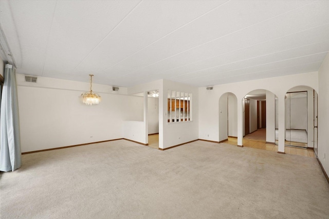 unfurnished living room with light colored carpet, baseboards, and arched walkways