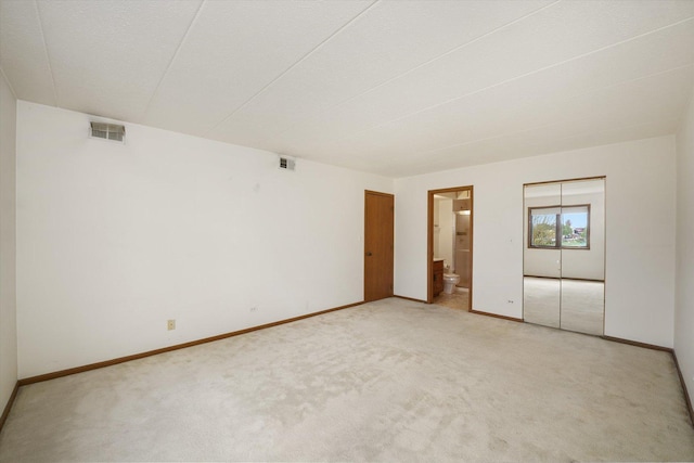 unfurnished bedroom with light colored carpet, baseboards, and ensuite bath