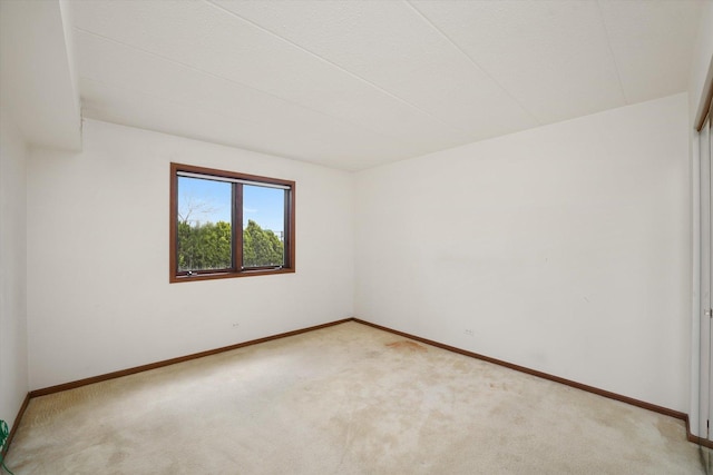 spare room with light colored carpet and baseboards