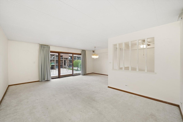 carpeted spare room with baseboards, a ceiling fan, and a chandelier