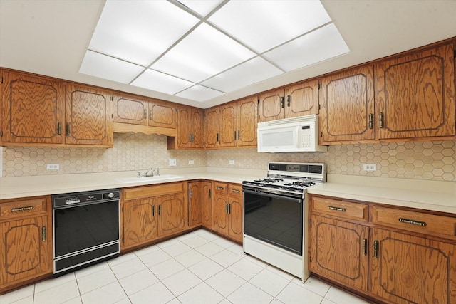 kitchen featuring white appliances, a sink, brown cabinetry, and light countertops