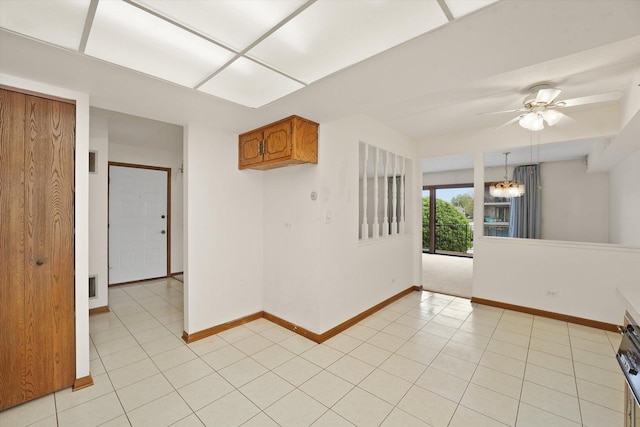 unfurnished room featuring baseboards, light tile patterned floors, and ceiling fan