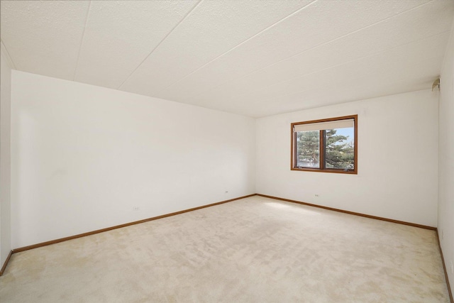 unfurnished room featuring light colored carpet and baseboards