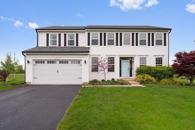 view of front of property featuring a garage, driveway, and a front yard