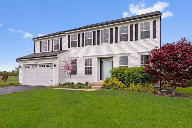 colonial home with a garage, driveway, and a front yard