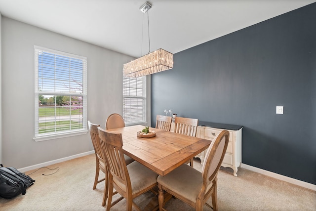 dining area featuring an inviting chandelier, light carpet, a wealth of natural light, and baseboards