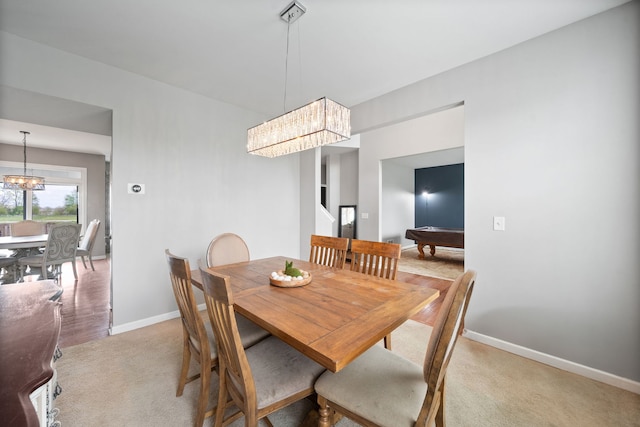 dining room with light colored carpet, baseboards, and a notable chandelier